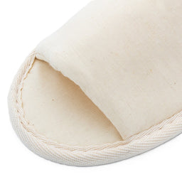 beige fabric slipper front, showing stitched edges and simple closed-toe design on white background