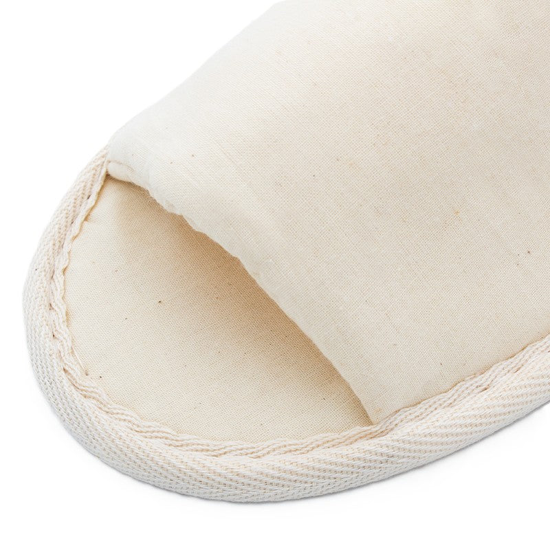 beige fabric slipper front, showing stitched edges and simple closed-toe design on white background