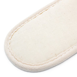 beige fabric slipper sole with stitched edges, showing its simple texture and design.