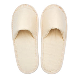 Pair of plain beige fabric slippers with closed toes, simple design, viewed from above on a white background.