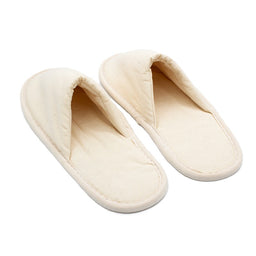 Pair of simple beige fabric slippers with closed toes, placed side by side on a white background