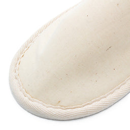 beige fabric slipper showing the stitched edge and texture of the material