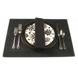 Table setting with black placemat, floral plate, black napkin, and stainless steel cutlery arranged neatly.