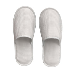 White generic waffle slippers with open toe and textured design, suitable for hotel or spa guests.