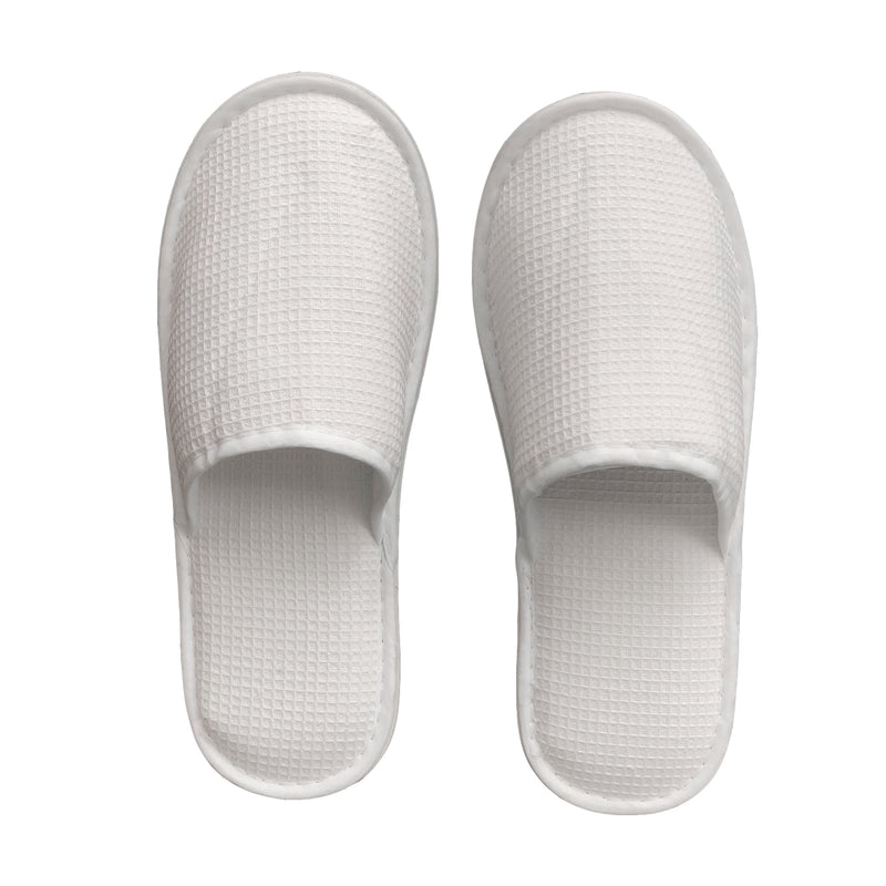 White generic waffle slippers with open toe and textured design, suitable for hotel or spa guests.