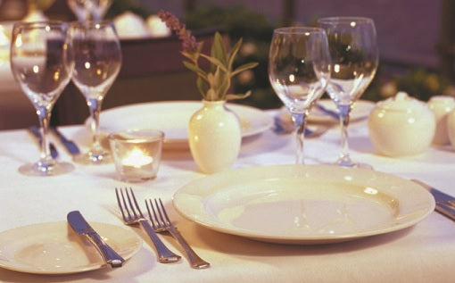 formal table setting with gold-accented cutlery, folded white napkin on plate, and wine glass