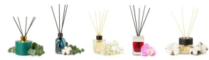 Five assorted reed diffusers in decorative bottles with floral accents placed around them.