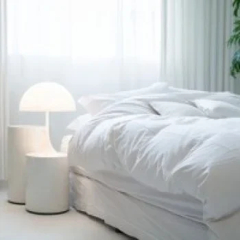 Cozy bedroom with an unmade white bed next to a modern white lamp and side table