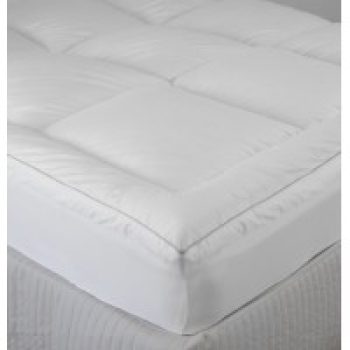Bed with white fluffy mattress topper and two white pillows in a cozy bedroom setting