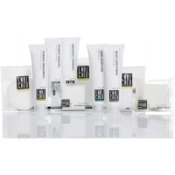Collection of white hotel toiletries including tubes, soaps, and amenities arranged neatly on a reflective surface.